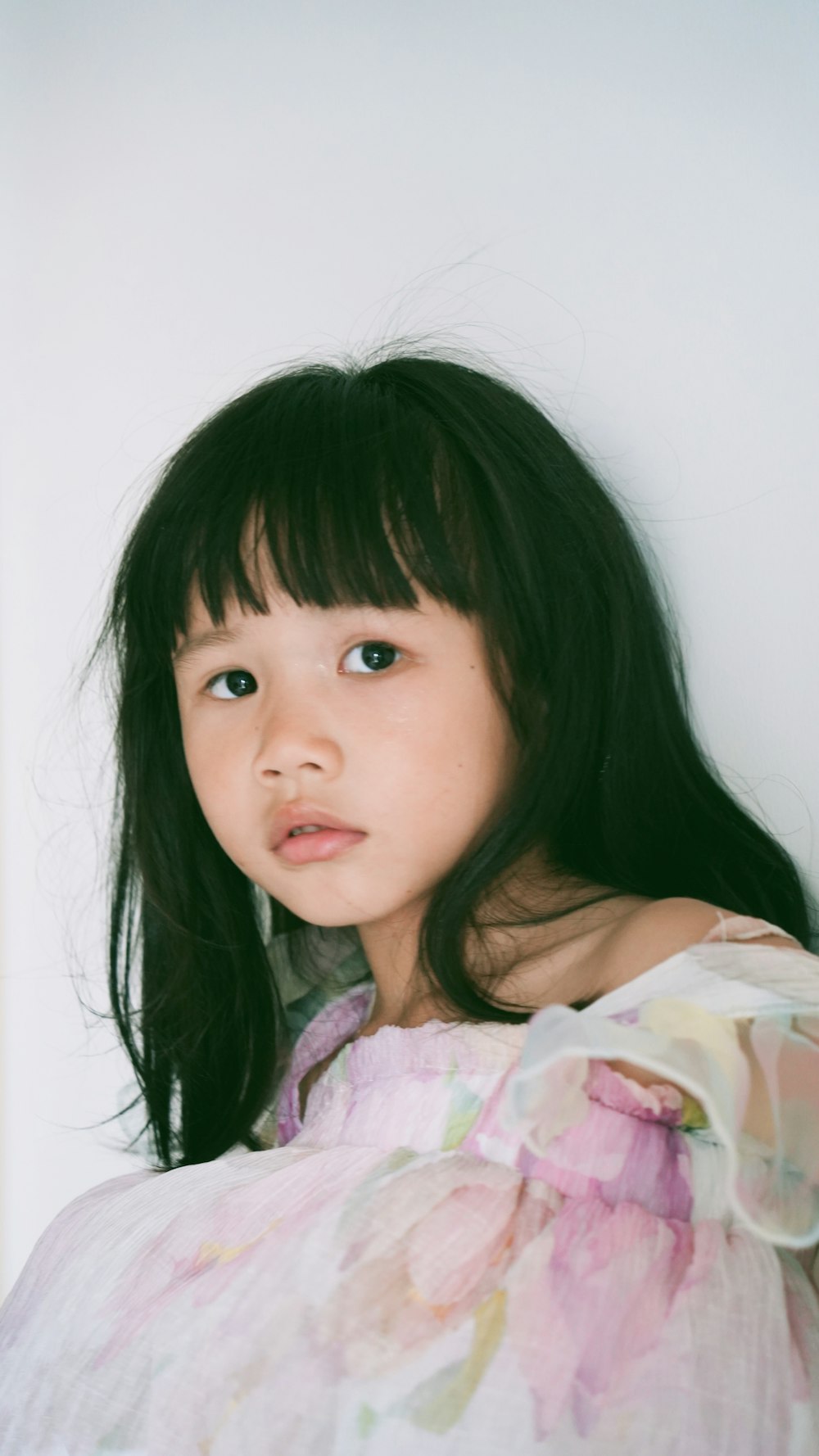 a little girl with long black hair wearing a dress