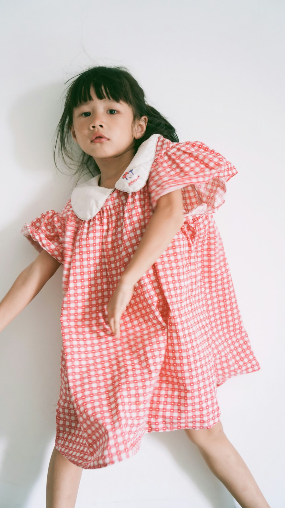 a little girl in a red and white dress