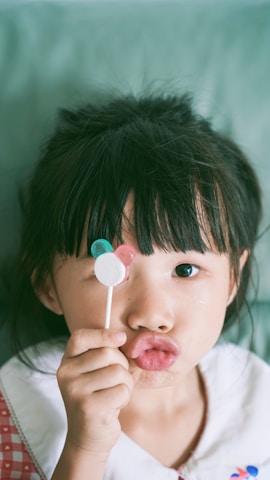 Close-up of a colorful Mickey-shaped ice cream treat held by a smiling child.