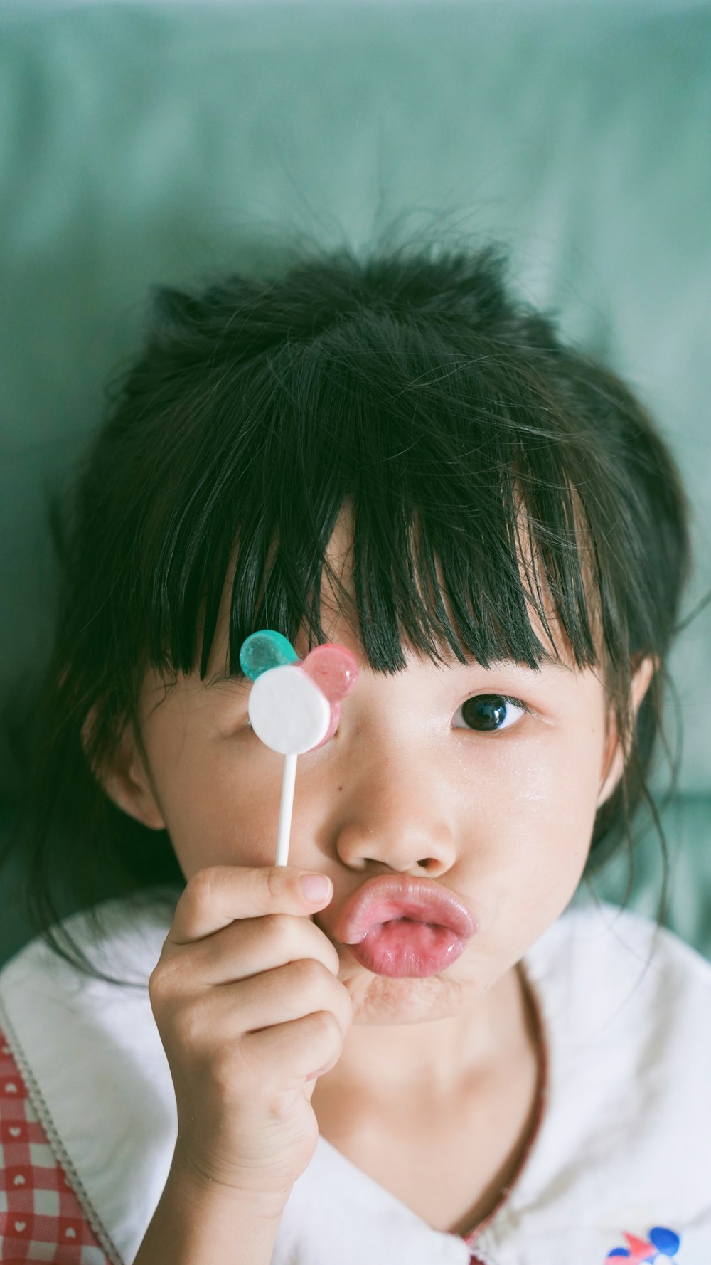 a little girl holding a lollipop in her mouth