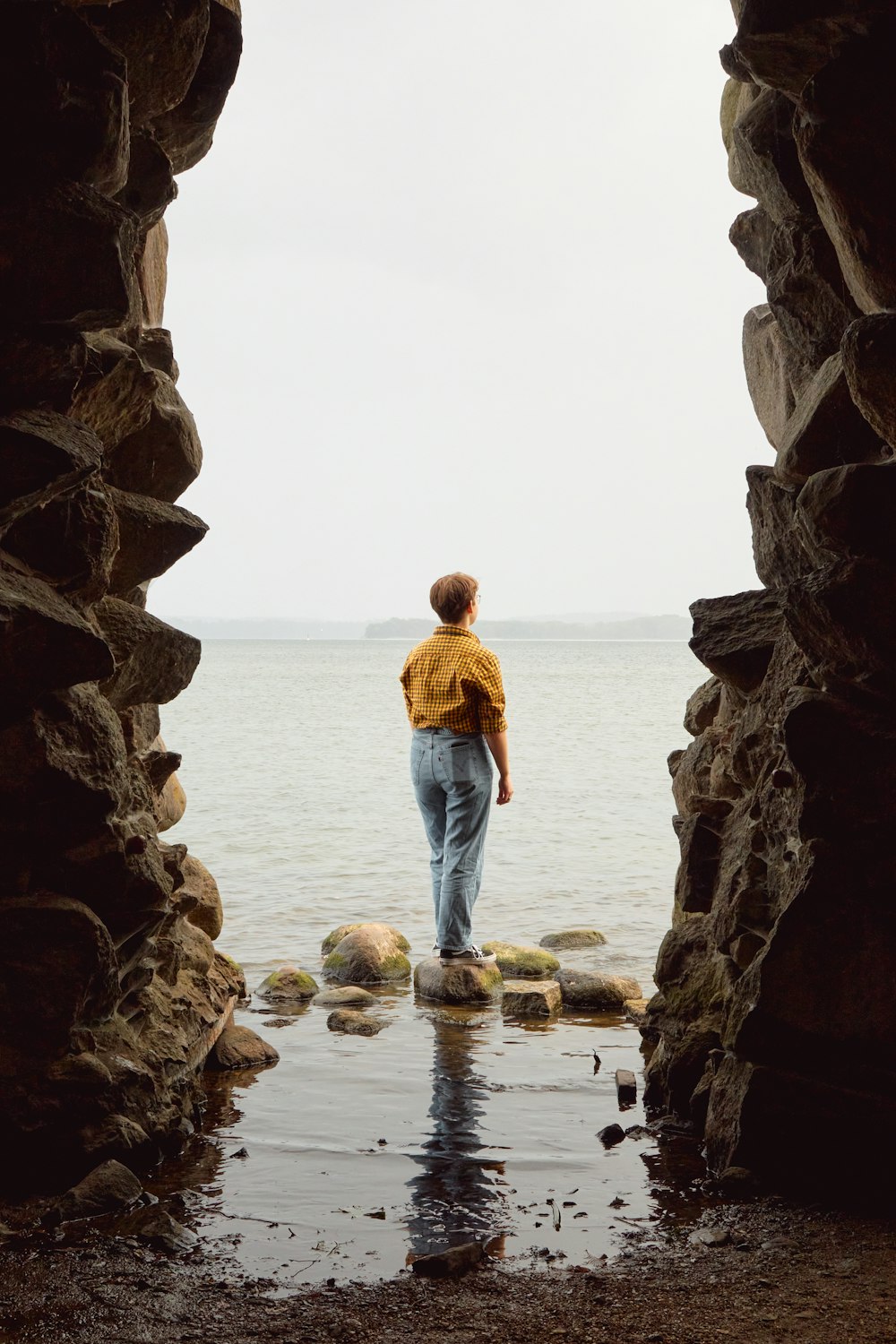a man standing in a doorway looking out at the ocean
