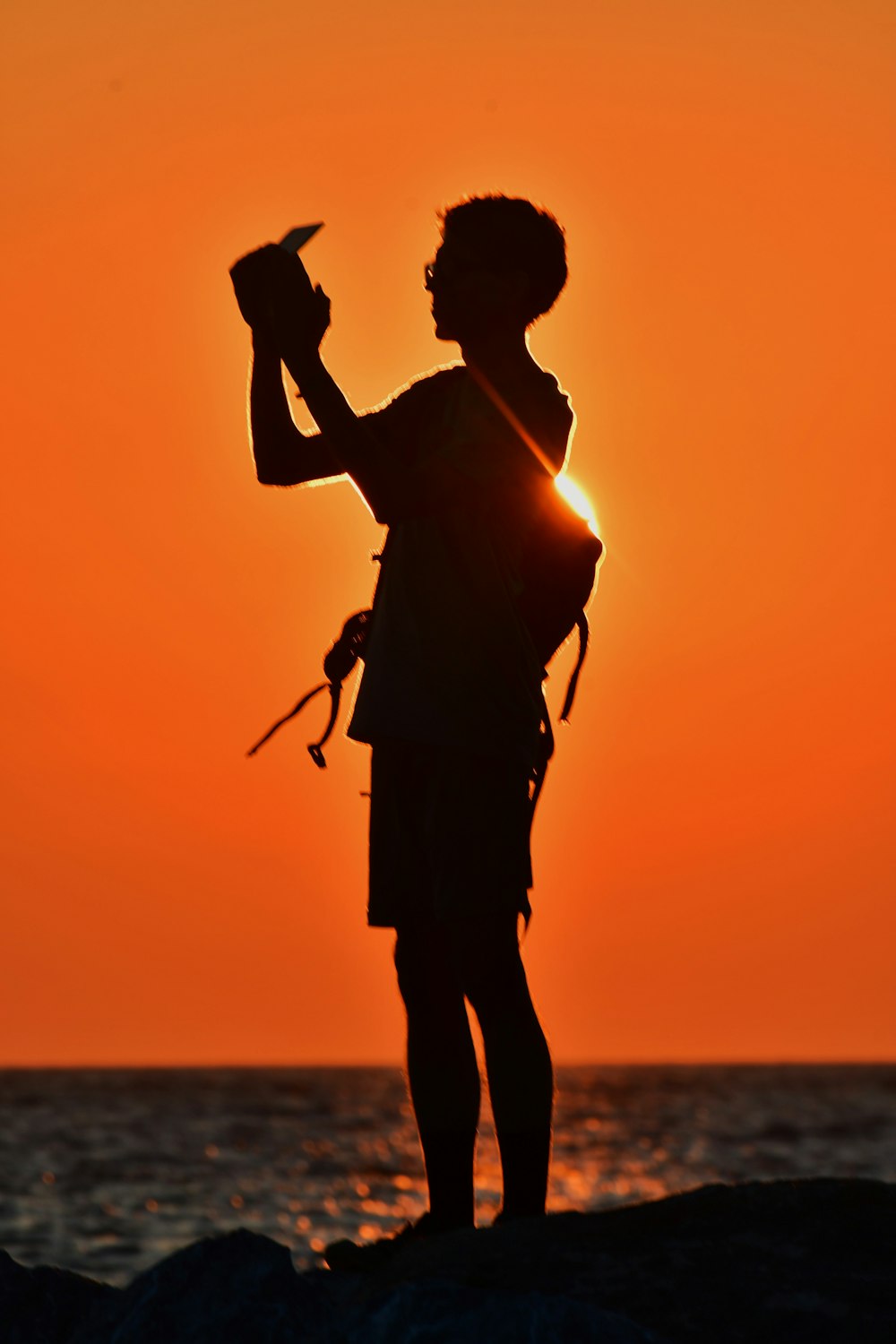 a silhouette of a person holding a camera at sunset