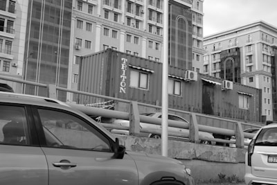 Monochrome photo of a cityscape with newspaper stands in the foreground.