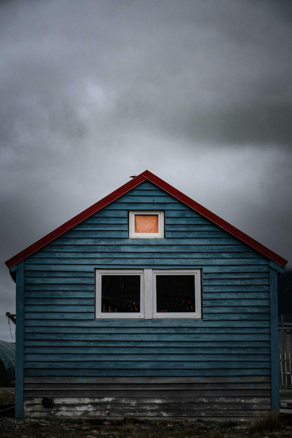 a blue house with a red roof and two windows