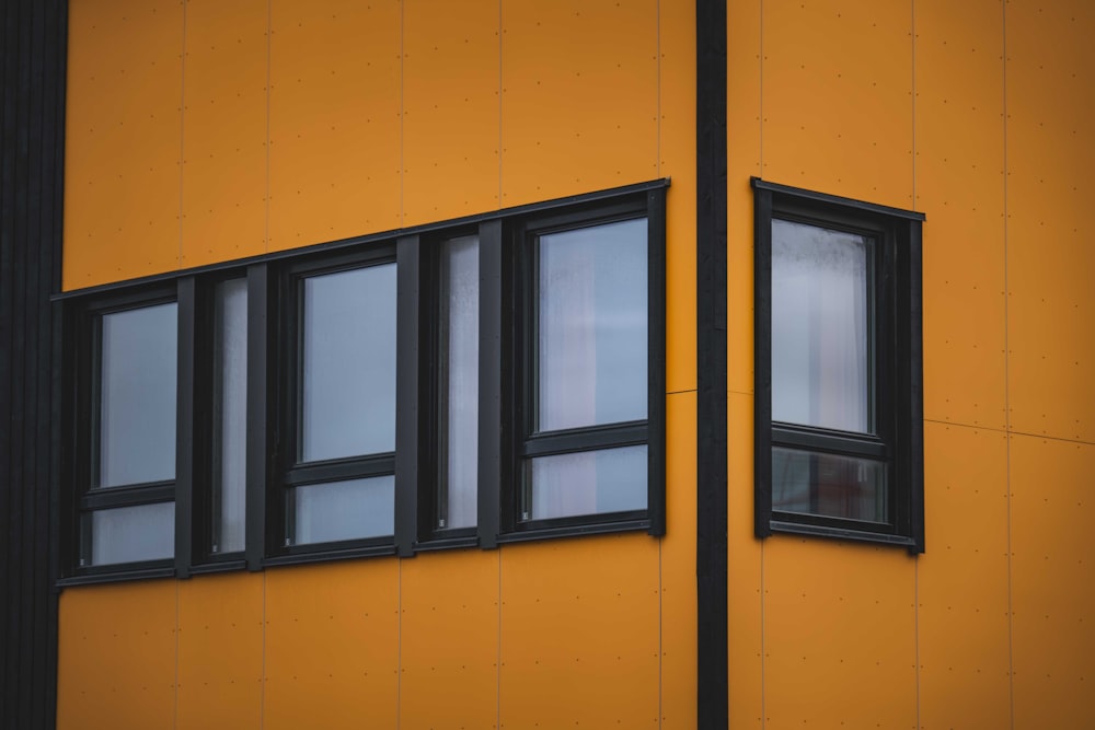 a yellow building with three windows and a black frame