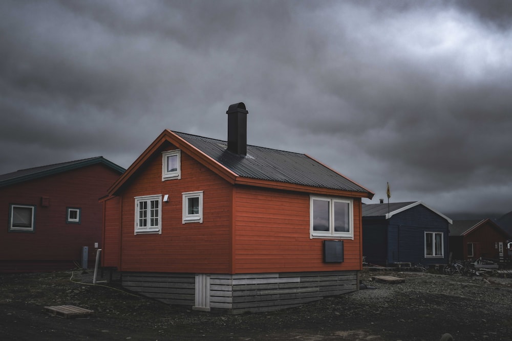 a red house sitting on top of a dirt field