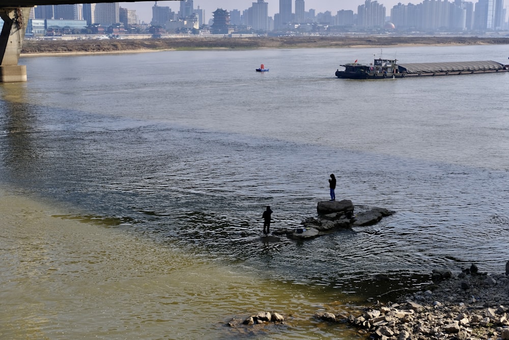 Un hombre parado sobre una roca en medio de un río