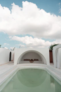 A sophisticated outdoor pool area featuring white textured walls and fine serif typography on signage.