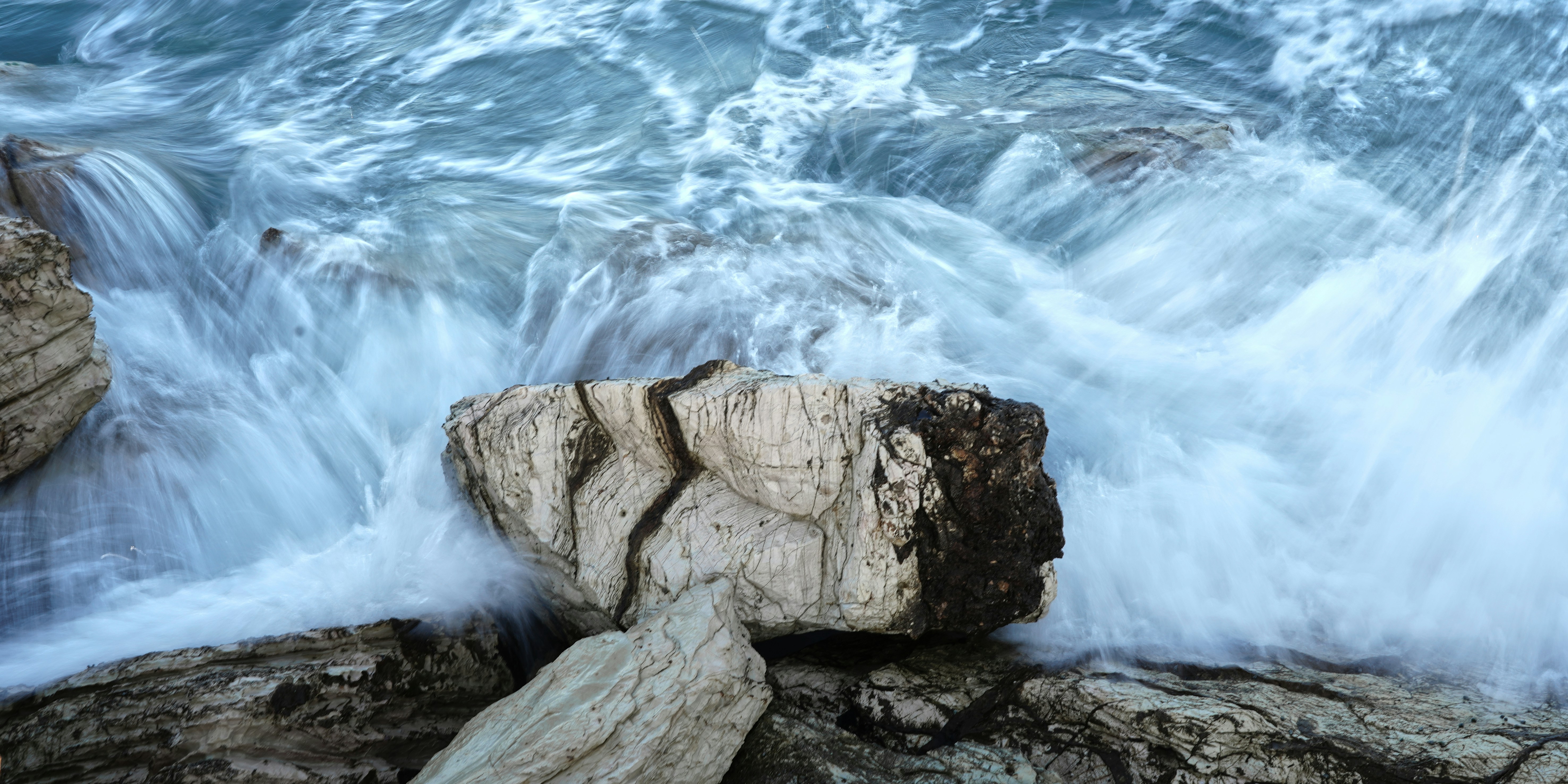 a large rock sitting next to a body of water