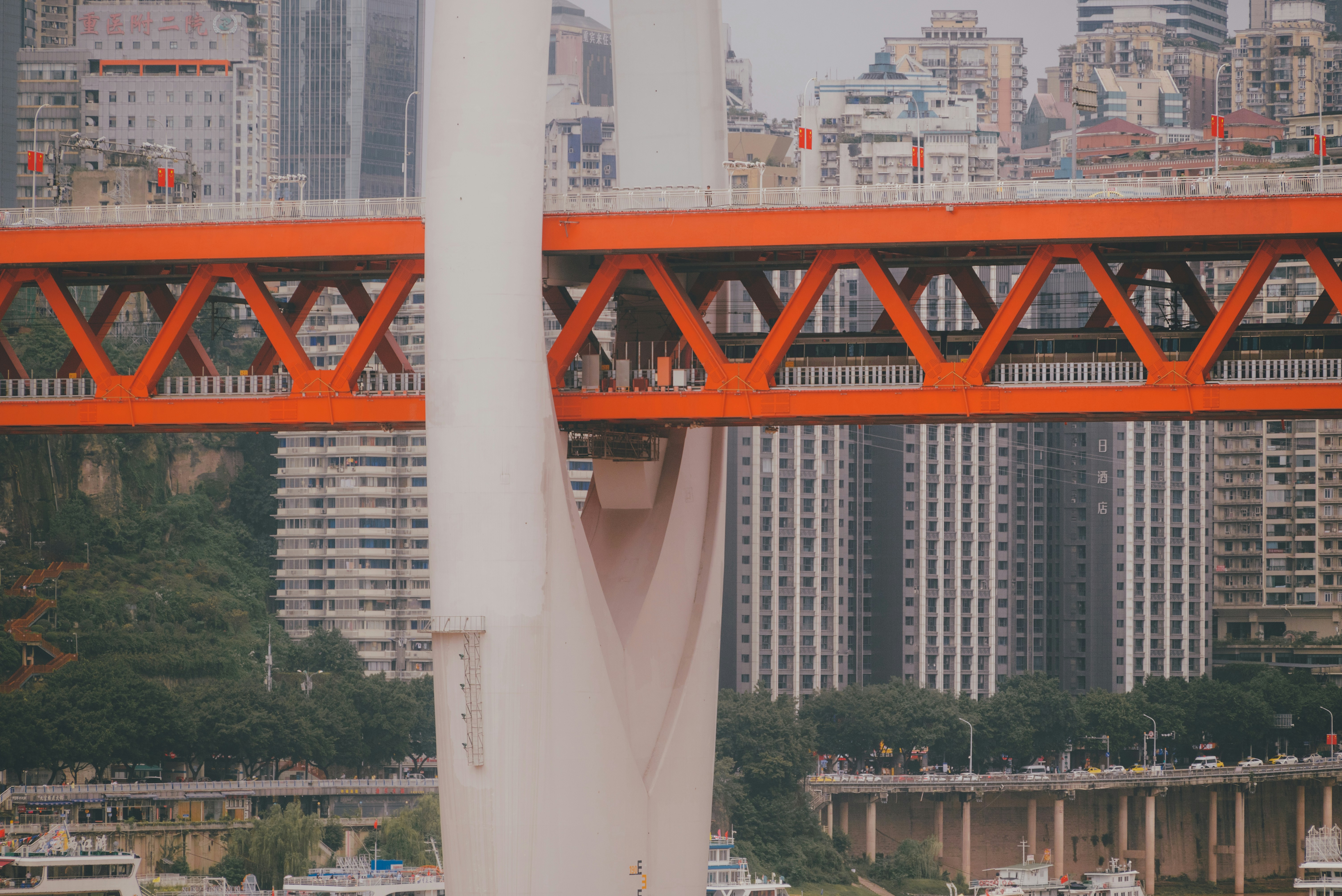 a red bridge over a body of water with a city in the background