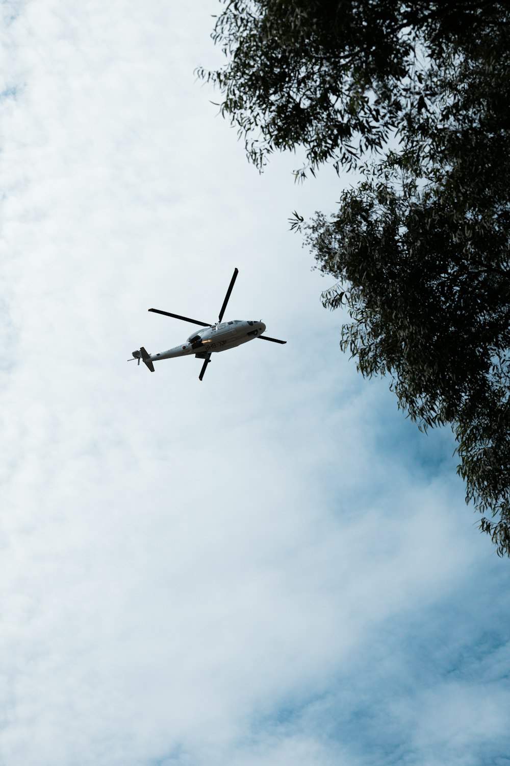 a helicopter flying through a cloudy blue sky