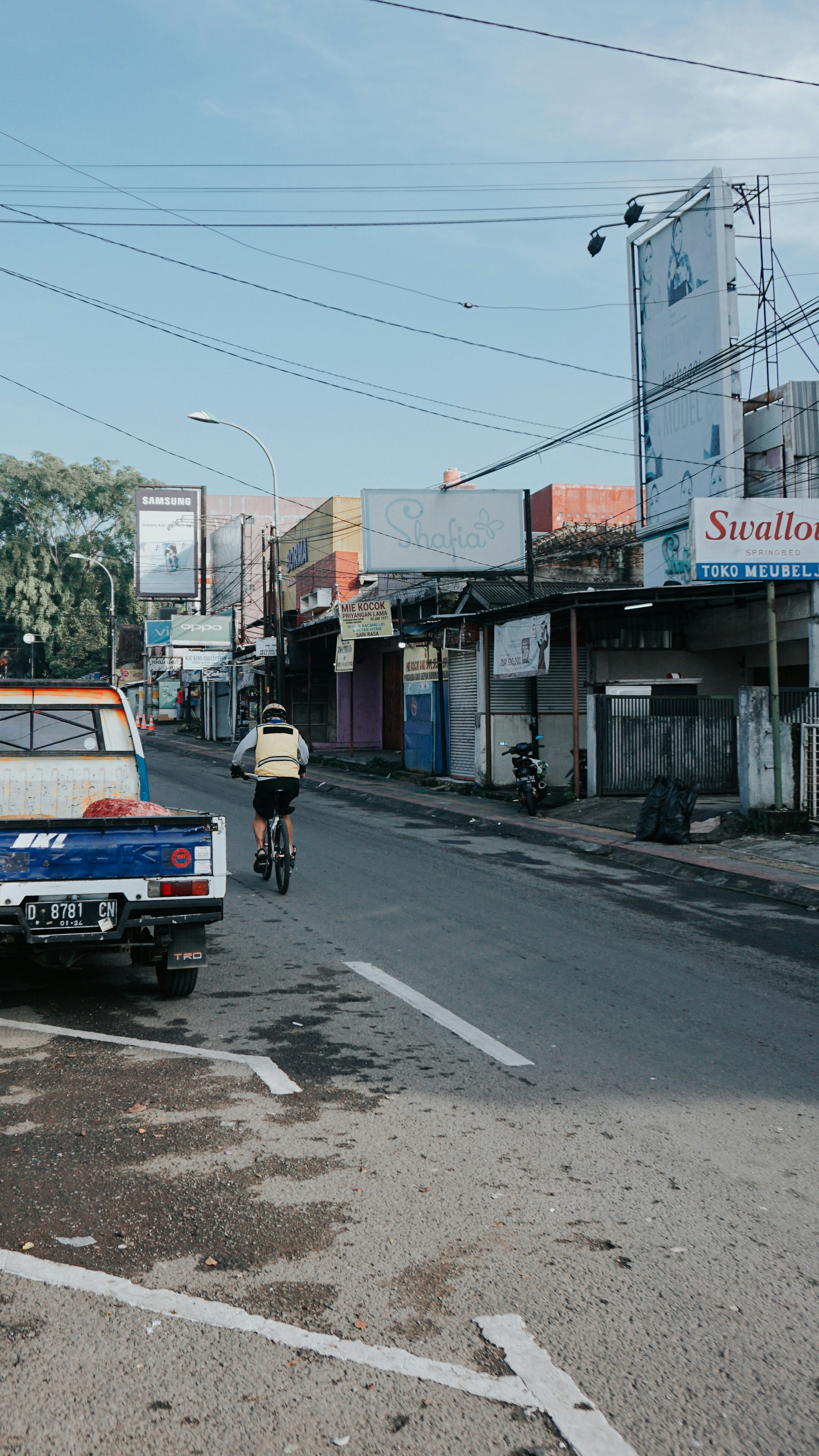 seorang pria mengendarai sepeda di jalan di sebelah truk