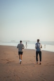 Runners jogging along the water’s edge with soft dawn light.