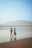 two people walking on a beach holding hands
