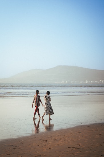 two people walking on a beach holding hands