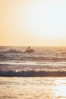 Jet skis speeding across the shimmering sea near a golden beach under a warm sunset