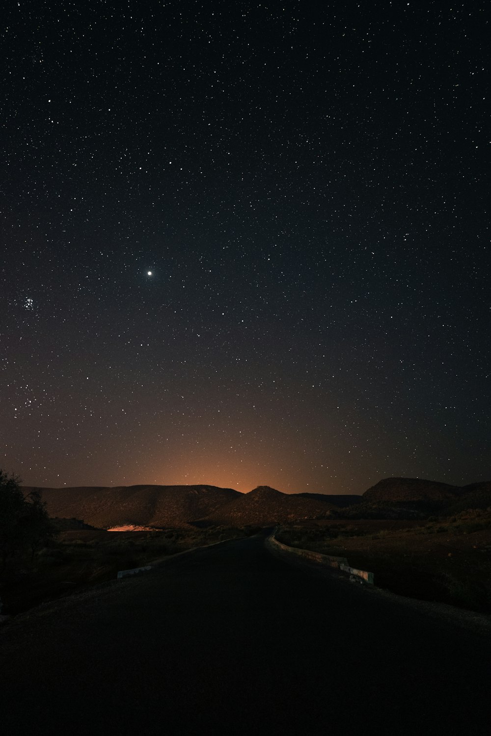 the night sky with stars above a road