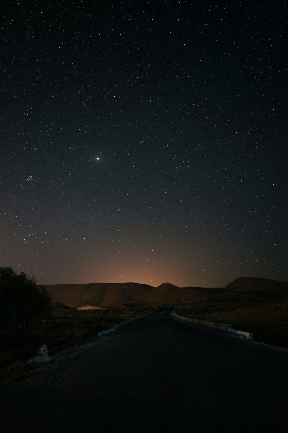the night sky with stars above a road