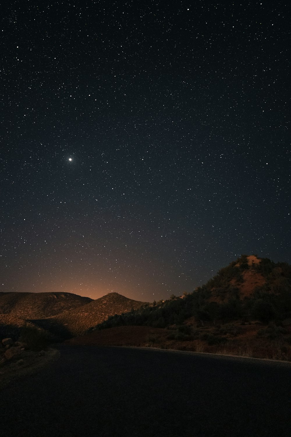 the night sky with stars above a mountain