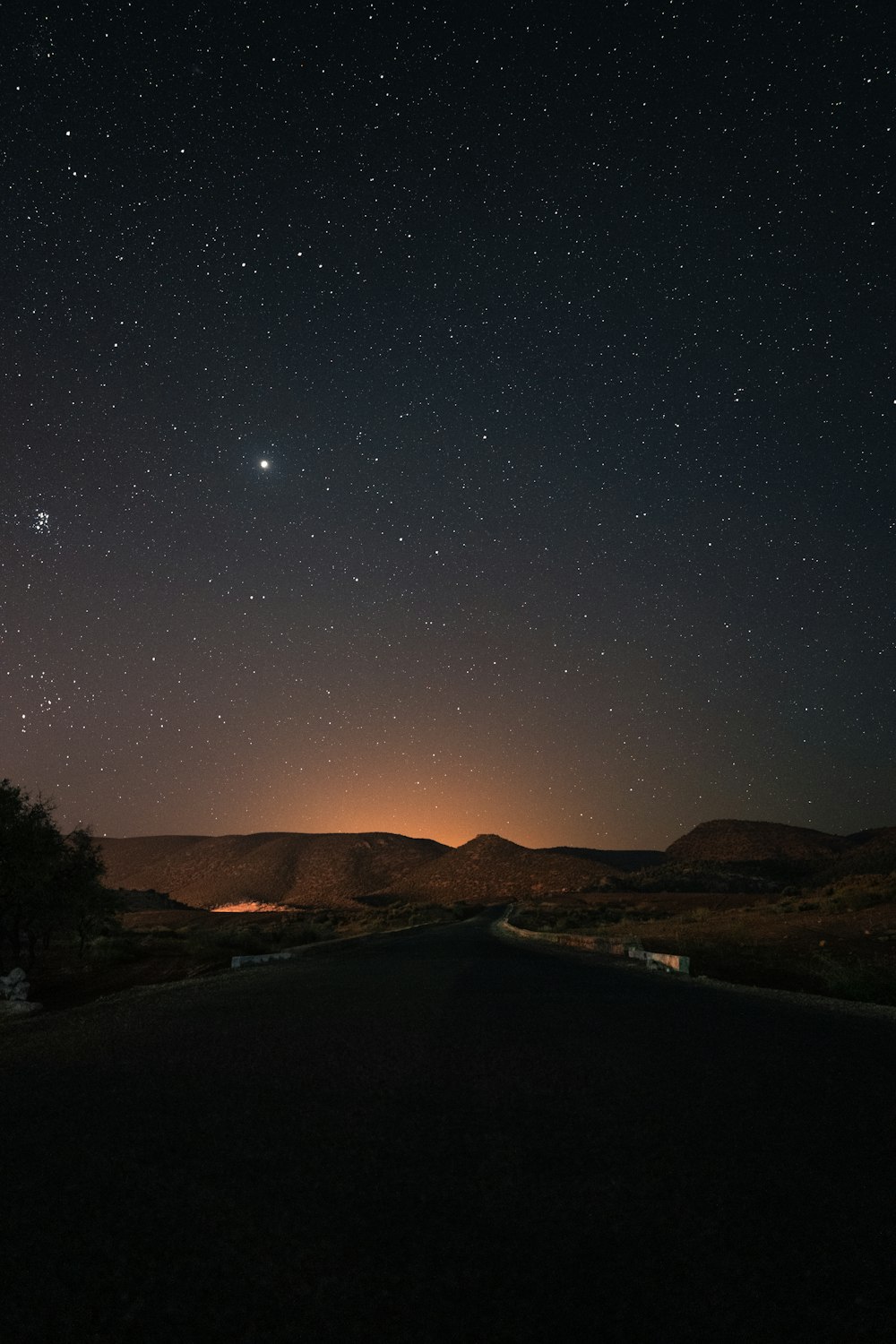 the night sky with stars above a road