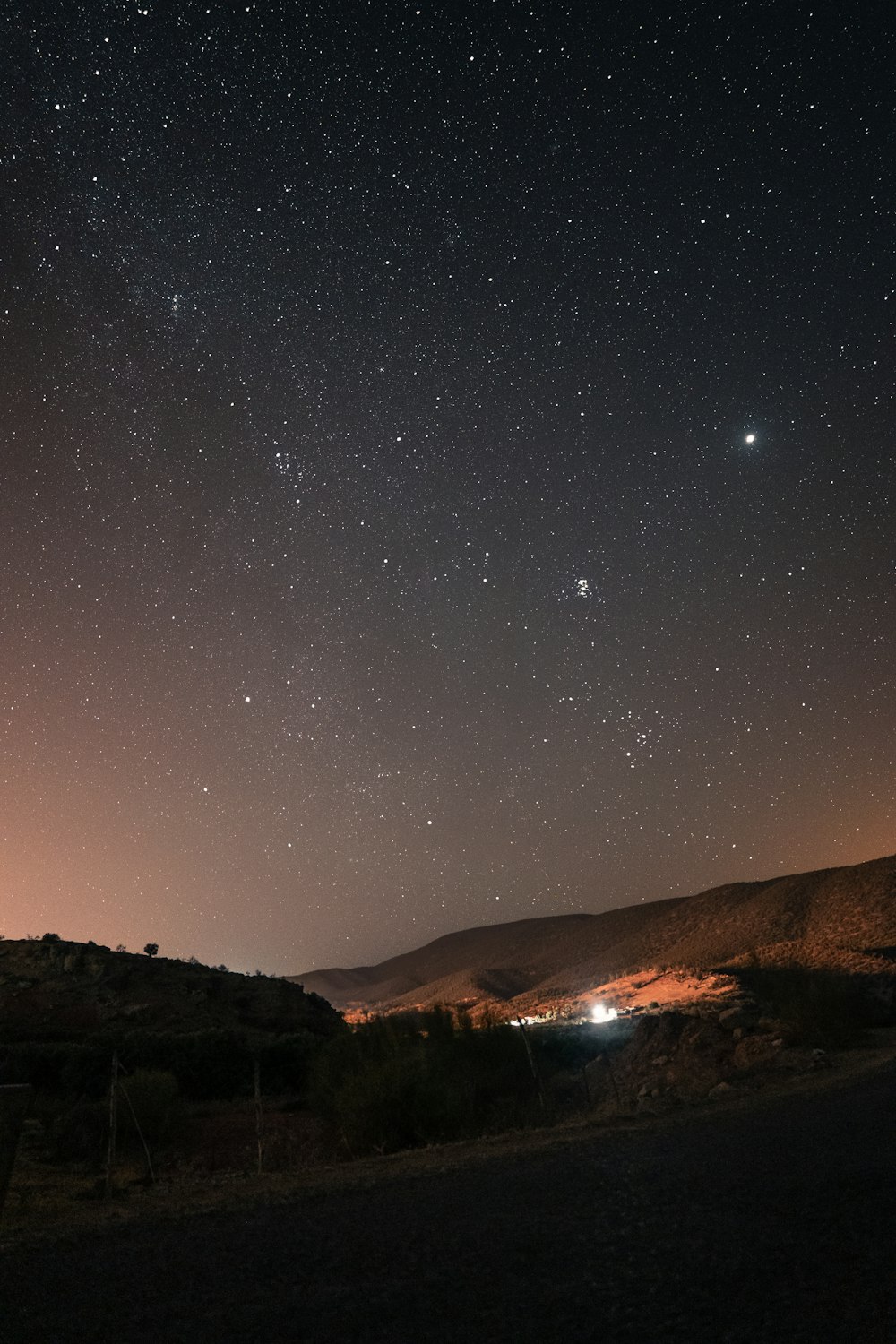 the night sky with stars above a mountain range