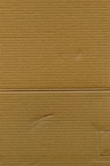 A close-up view of corrugated cardboard with vertical and horizontal lines visible. The texture is coarse, with subtle variations in color and subtle markings suggesting folds or creases.