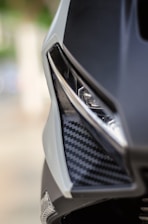 Close-up of a sleek carbon fiber auto part installed on a luxury car under natural light.