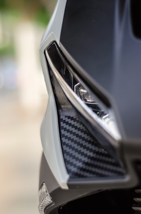 Close-up of a sleek carbon fiber auto part installed on a luxury car under natural light.