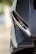 Close-up of an angular car headlight on a modern vehicle featuring sleek lines and carbon fiber detailing.