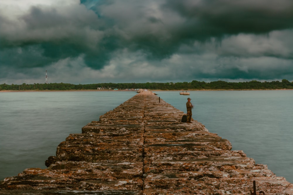a man is standing on a long pier