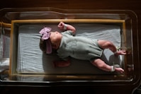 a baby laying on a bed with a pink headband