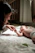 A smiling mother gently encouraging her baby during a tummy time session in a cozy, bright room.