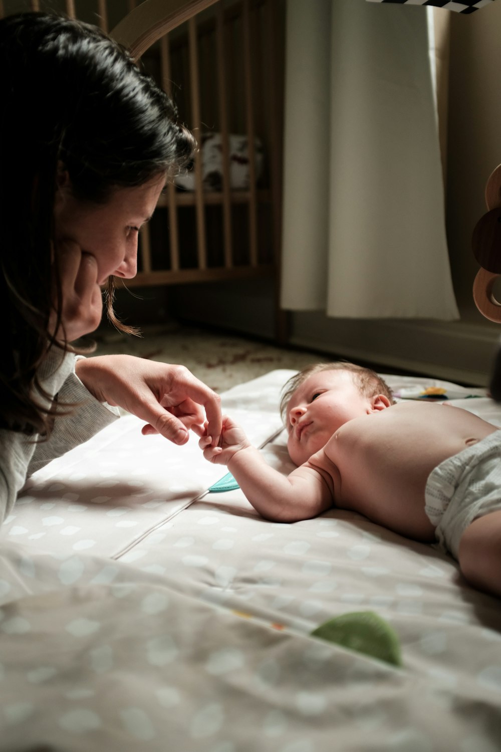 a woman is touching a baby's hand on a bed