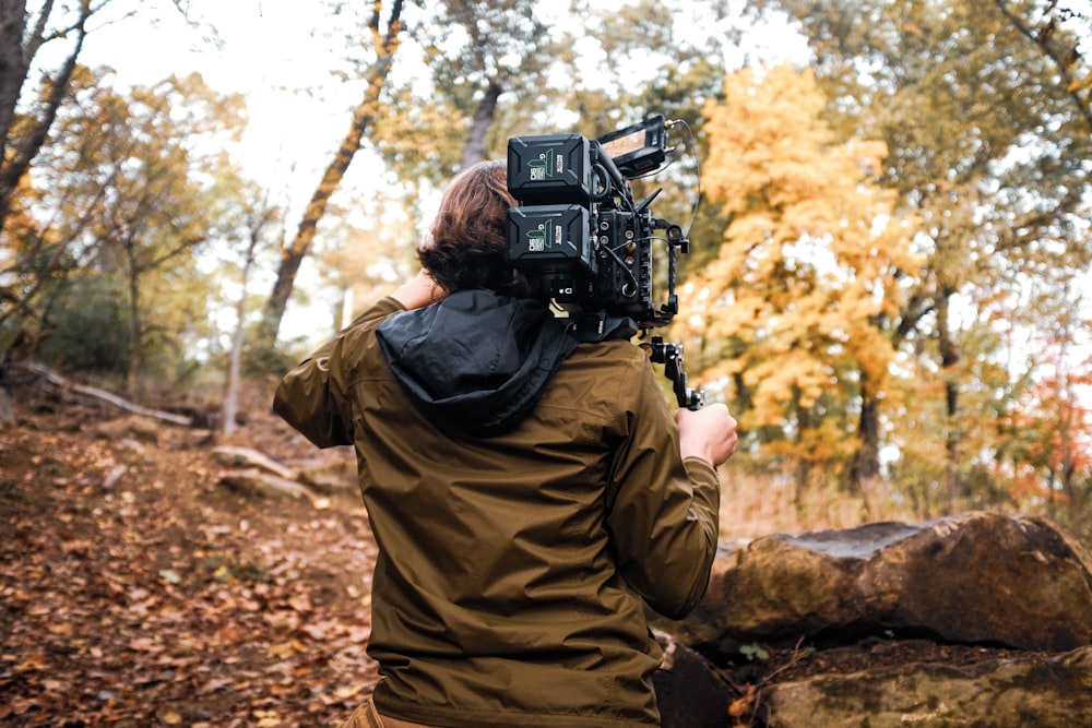 a man holding a camera in a wooded area
