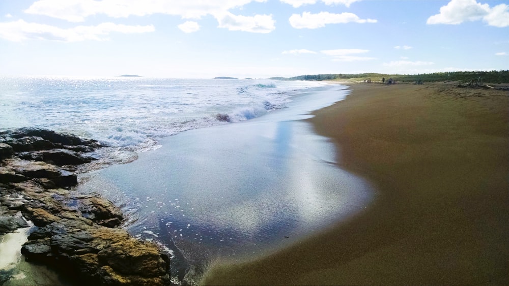 a sandy beach with waves coming in from the ocean