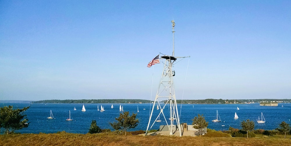 a windmill with a flag on top of it next to a body of water