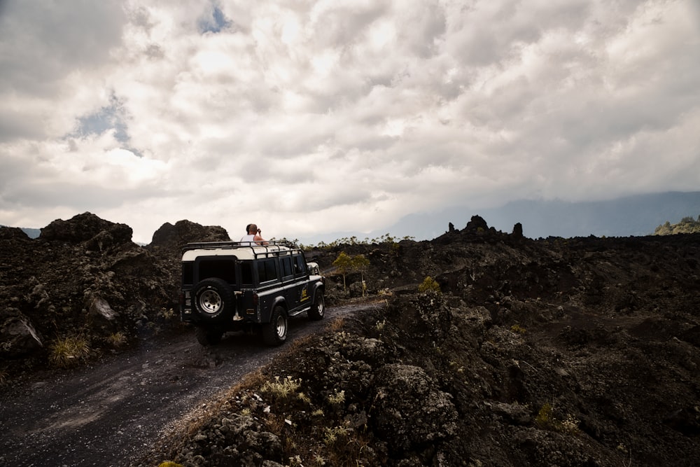 a man standing on top of a vehicle on a dirt road