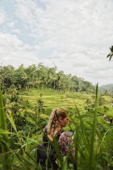 A traveler happily booking a trip on a sleek laptop with tropical Indonesian landscapes in the background