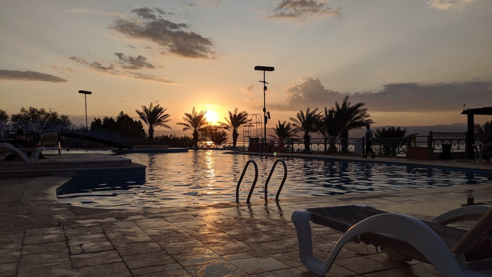 the sun is setting over a swimming pool