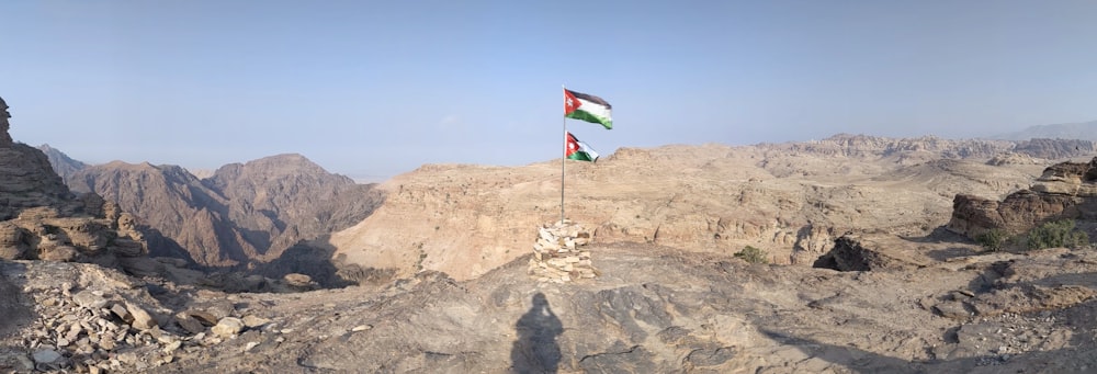 two flags flying on top of a rocky mountain