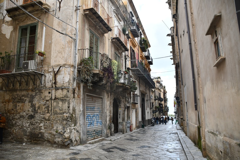 a narrow city street with people walking down it