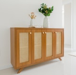 a wooden cabinet with two vases on top of it