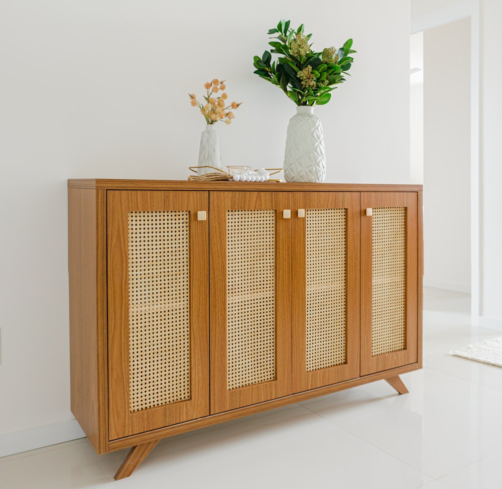 a wooden cabinet with two vases on top of it