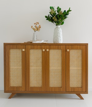 A rattan dining bench paired with a metal frame sideboard cabinet, blending textures beautifully.
