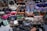 A large assortment of designer handbags displayed closely together. The collection includes various styles, colors, and brands, each featuring distinct textures and patterns. Some bags have visible brand logos and metal hardware accents.