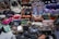 A large assortment of designer handbags displayed closely together. The collection includes various styles, colors, and brands, each featuring distinct textures and patterns. Some bags have visible brand logos and metal hardware accents.