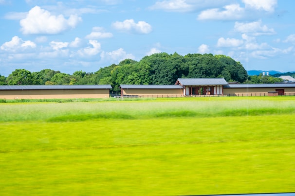 A serene landscape featuring a traditional kiln surrounded by greenery.