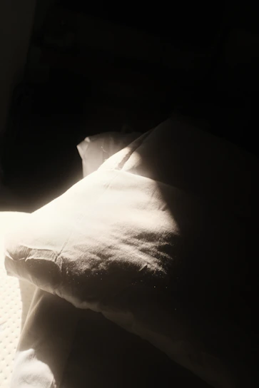 A soft linen pillow sham resting on a sunlit window bench with gentle folds.