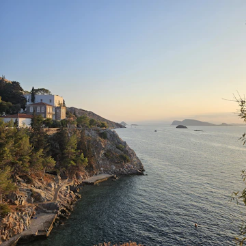 Cozy beachfront house surrounded by lush greenery at sunset.