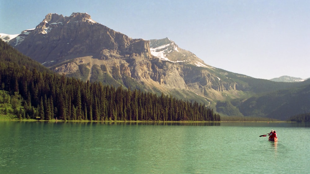 a person standing in a lake with mountains in the background